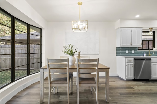 dining area featuring dark wood-type flooring, sink, and a chandelier