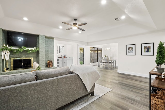 bedroom featuring a raised ceiling, a fireplace, and light hardwood / wood-style flooring