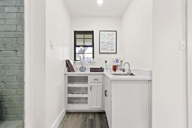 bar with dark hardwood / wood-style floors, sink, and white cabinets