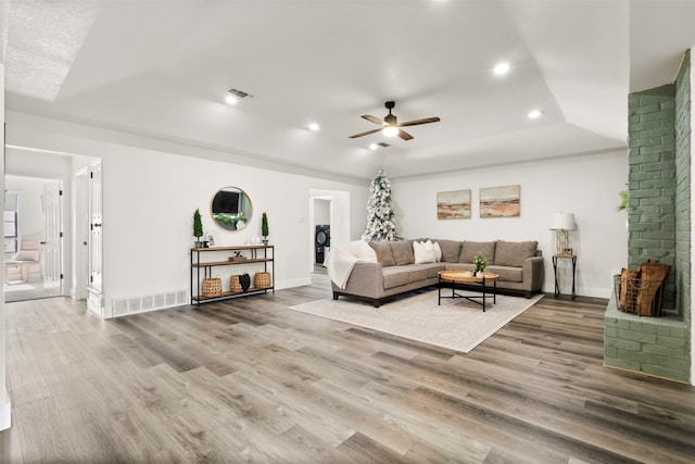 living room with a tray ceiling, wood-type flooring, and ceiling fan