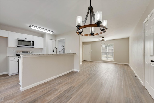 kitchen with white cabinets, light stone countertops, hanging light fixtures, and appliances with stainless steel finishes