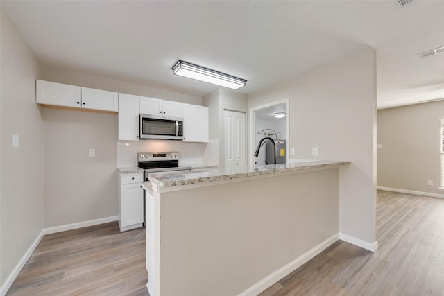 kitchen with light stone counters, light hardwood / wood-style flooring, white cabinets, and stainless steel appliances