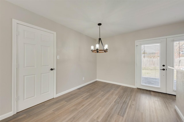 unfurnished room featuring a notable chandelier and light wood-type flooring