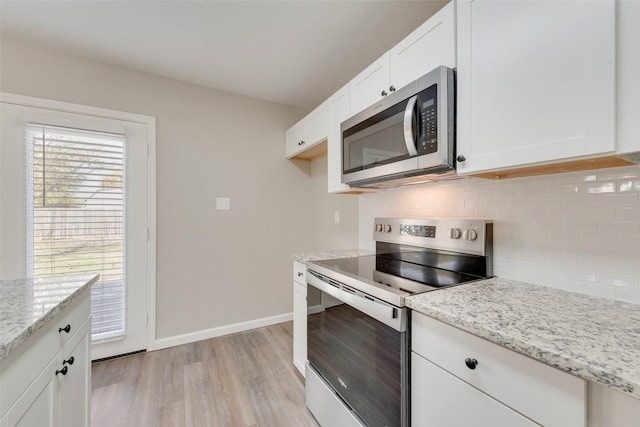 kitchen featuring light stone countertops, light wood-type flooring, tasteful backsplash, stainless steel appliances, and white cabinets