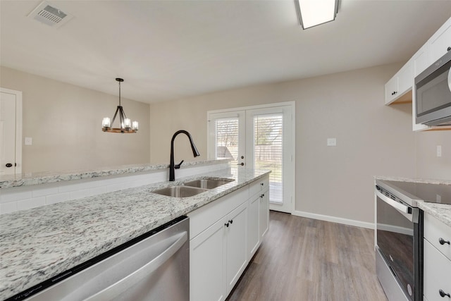 kitchen featuring light stone countertops, appliances with stainless steel finishes, sink, a chandelier, and white cabinetry