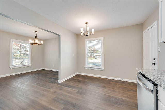 unfurnished dining area with dark hardwood / wood-style flooring and an inviting chandelier