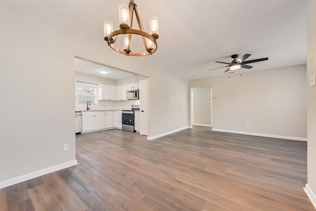 unfurnished living room with hardwood / wood-style flooring and ceiling fan with notable chandelier