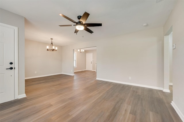 unfurnished room with ceiling fan with notable chandelier and hardwood / wood-style flooring