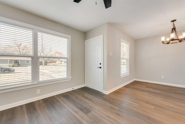 unfurnished room with ceiling fan with notable chandelier and wood-type flooring