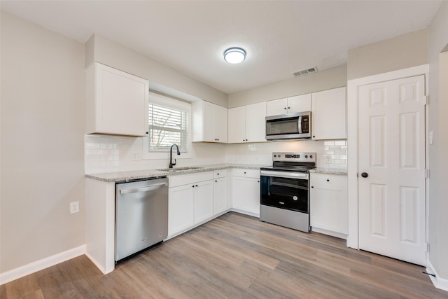 kitchen featuring white cabinets, appliances with stainless steel finishes, light hardwood / wood-style floors, and sink