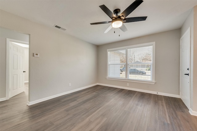 empty room with dark hardwood / wood-style flooring and ceiling fan