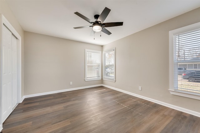 empty room featuring ceiling fan, a healthy amount of sunlight, and dark hardwood / wood-style flooring