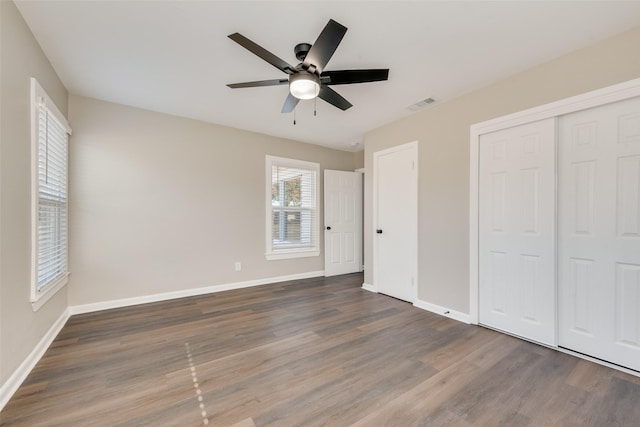 unfurnished bedroom featuring a closet, ceiling fan, and dark wood-type flooring