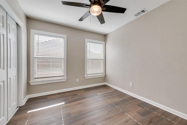 unfurnished room with dark hardwood / wood-style floors, a wealth of natural light, and ceiling fan