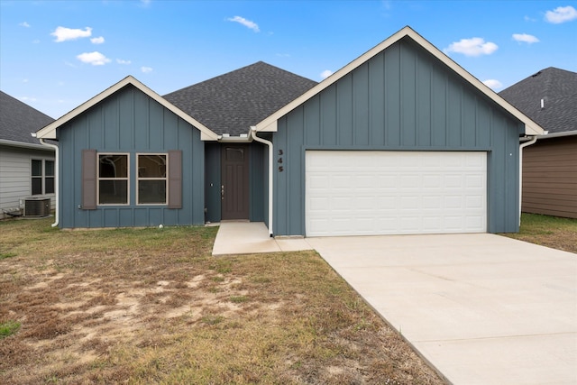 view of front of home with central AC unit, a garage, and a front yard