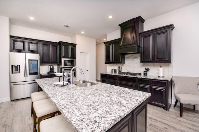 1927 Frediano Ln, Mclendon Chisholm, TX 75032 - kitchen with appliances with stainless steel finishes, custom exhaust hood, a sink, light wood-style floors, and tasteful backsplash