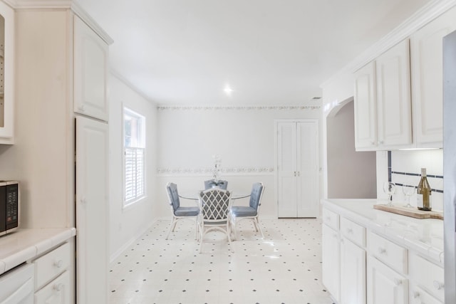 dining area with arched walkways, baseboards, and light floors