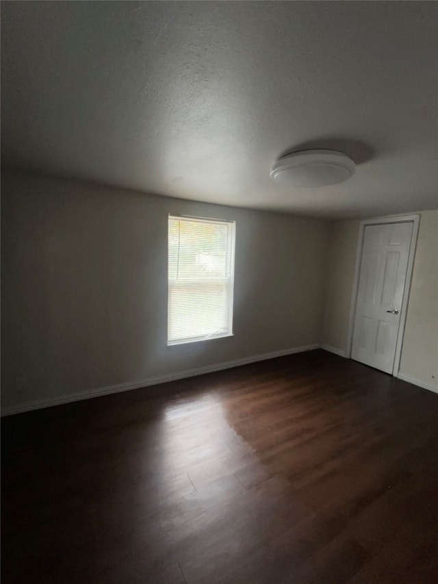 spare room with a textured ceiling and dark wood-type flooring