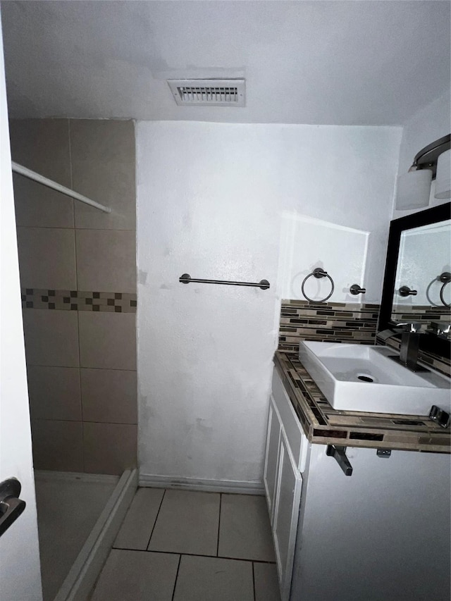 bathroom with tile patterned flooring, sink, and decorative backsplash