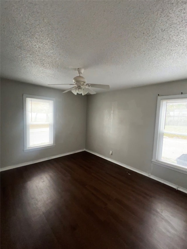 spare room with a textured ceiling, ceiling fan, and dark wood-type flooring