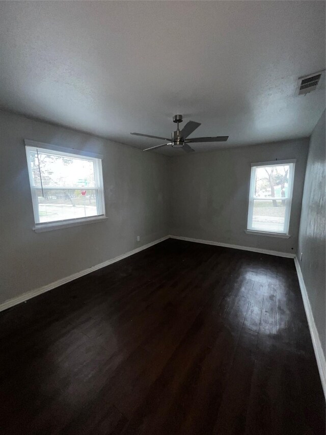 spare room featuring a textured ceiling, dark hardwood / wood-style floors, plenty of natural light, and ceiling fan