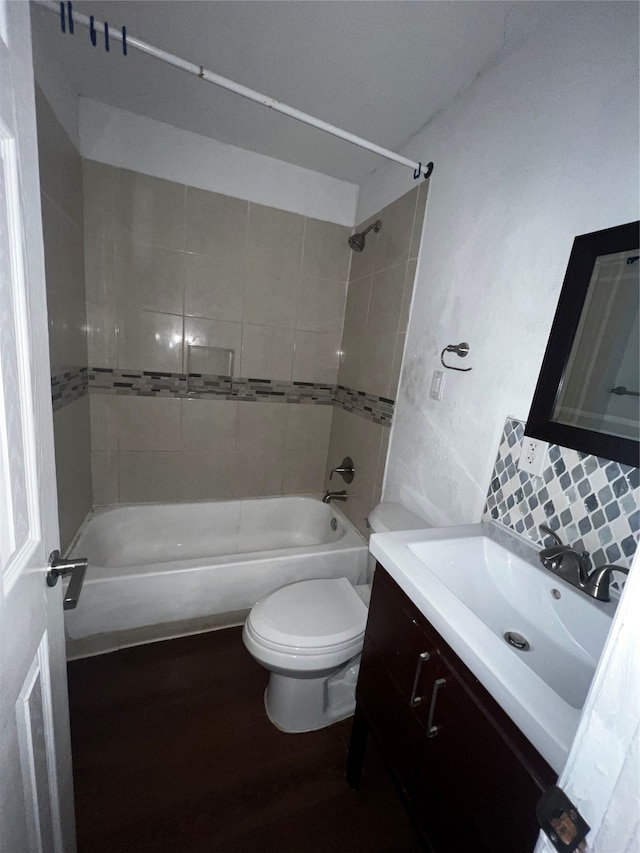 full bathroom featuring vanity, wood-type flooring, tiled shower / bath combo, and toilet