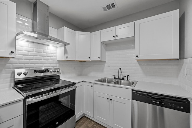 kitchen with wall chimney exhaust hood, appliances with stainless steel finishes, sink, and white cabinets