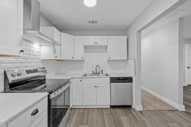 kitchen featuring sink, wall chimney range hood, white cabinetry, stainless steel appliances, and tasteful backsplash