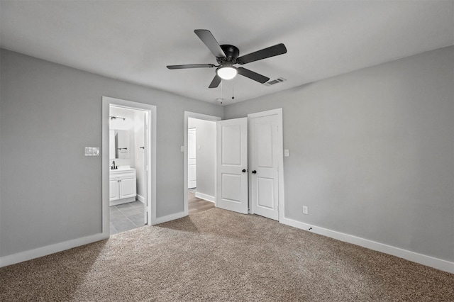 unfurnished bedroom featuring ceiling fan, light colored carpet, connected bathroom, and a closet