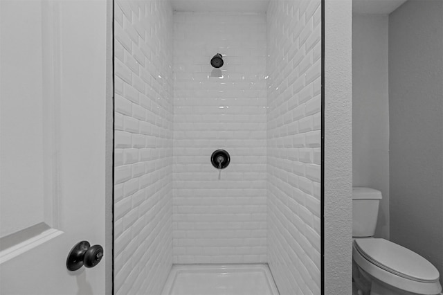 bathroom featuring a tile shower and toilet