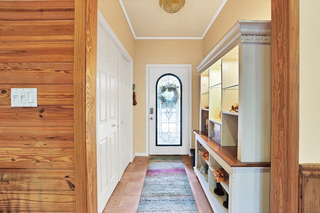 entryway with light tile patterned floors and ornamental molding