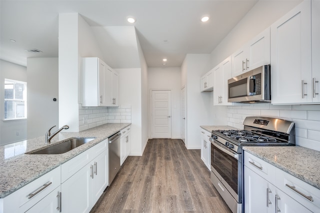 kitchen with light stone countertops, appliances with stainless steel finishes, sink, and white cabinets