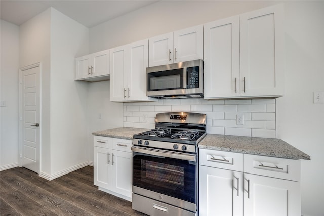 kitchen with white cabinetry, light stone counters, dark hardwood / wood-style floors, stainless steel appliances, and backsplash