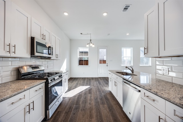 kitchen featuring white cabinetry, sink, stainless steel appliances, dark hardwood / wood-style floors, and decorative light fixtures