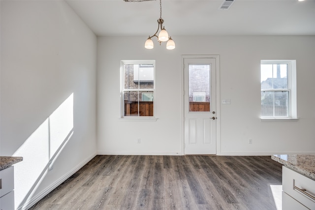 unfurnished dining area featuring wood-type flooring and an inviting chandelier