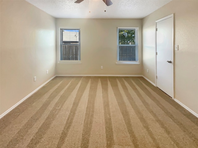 spare room with a textured ceiling, carpet floors, and a wealth of natural light