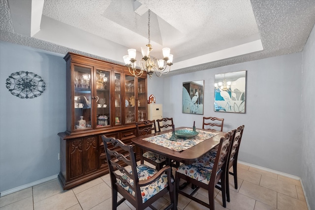 dining room featuring a raised ceiling, light tile patterned flooring, a textured ceiling, and an inviting chandelier