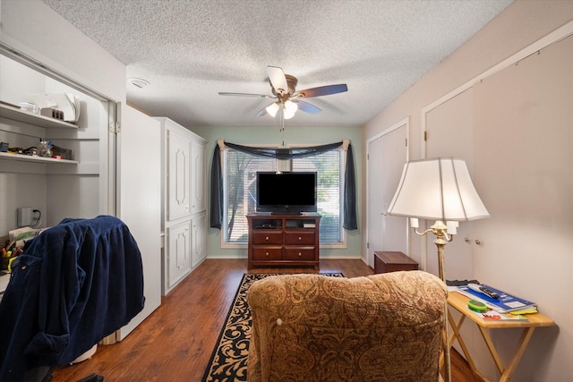 bedroom with ceiling fan, dark wood-type flooring, and a textured ceiling