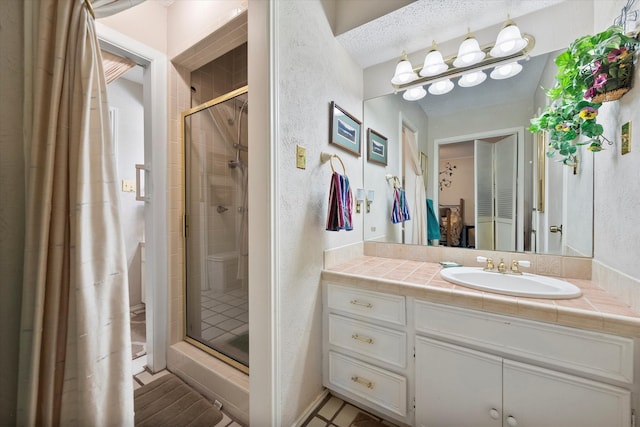 bathroom with vanity, a shower with shower door, and a textured ceiling