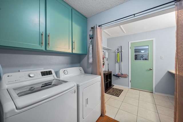 laundry area featuring washer and dryer, cabinets, light tile patterned floors, and a textured ceiling