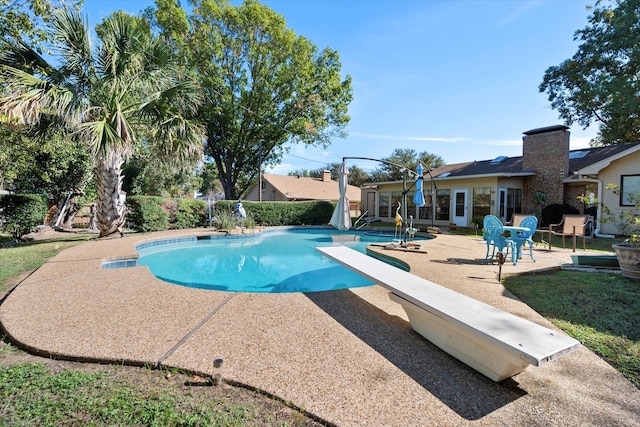 view of pool with a diving board and a patio