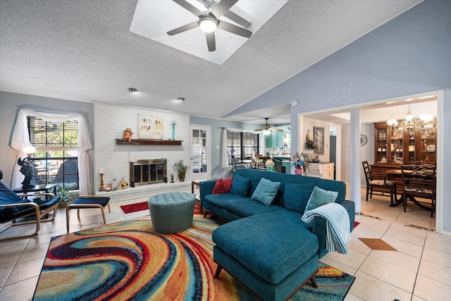 living room featuring ceiling fan with notable chandelier, light tile patterned flooring, and a brick fireplace