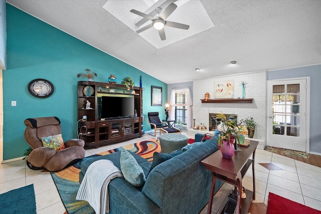 tiled living room featuring a textured ceiling, ceiling fan, lofted ceiling, and a brick fireplace