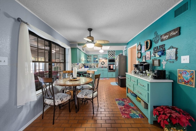 dining space with ceiling fan, dark tile patterned flooring, and a textured ceiling