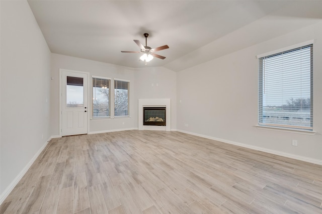 unfurnished living room with ceiling fan, vaulted ceiling, and light wood-type flooring