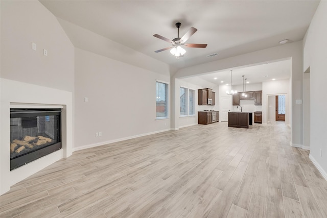 unfurnished living room with ceiling fan, sink, and light wood-type flooring