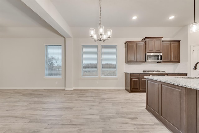 kitchen with pendant lighting, sink, light stone counters, and appliances with stainless steel finishes