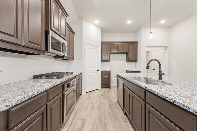 kitchen with appliances with stainless steel finishes, hanging light fixtures, sink, and dark brown cabinets