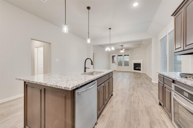 kitchen with sink, appliances with stainless steel finishes, an island with sink, vaulted ceiling, and light wood-type flooring