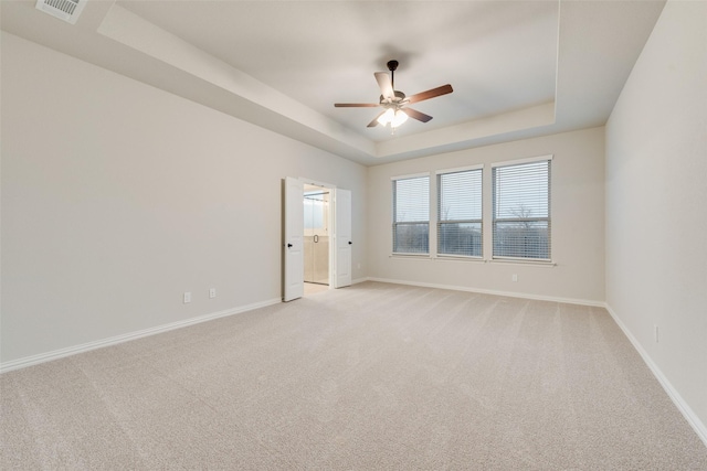 unfurnished room featuring light colored carpet, ceiling fan, and a tray ceiling